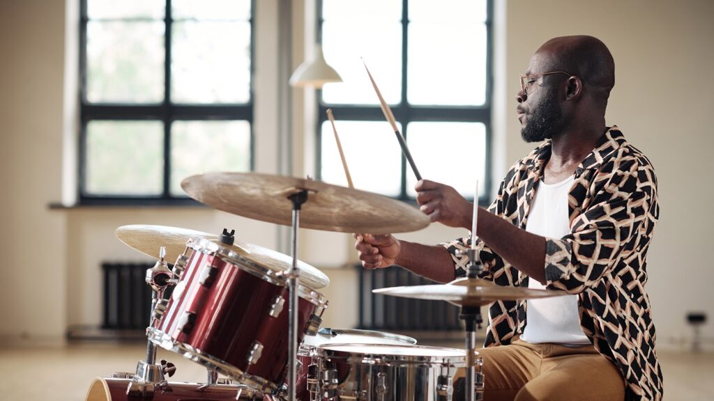 African drummer practicing to play drums sitting at drums set at studio