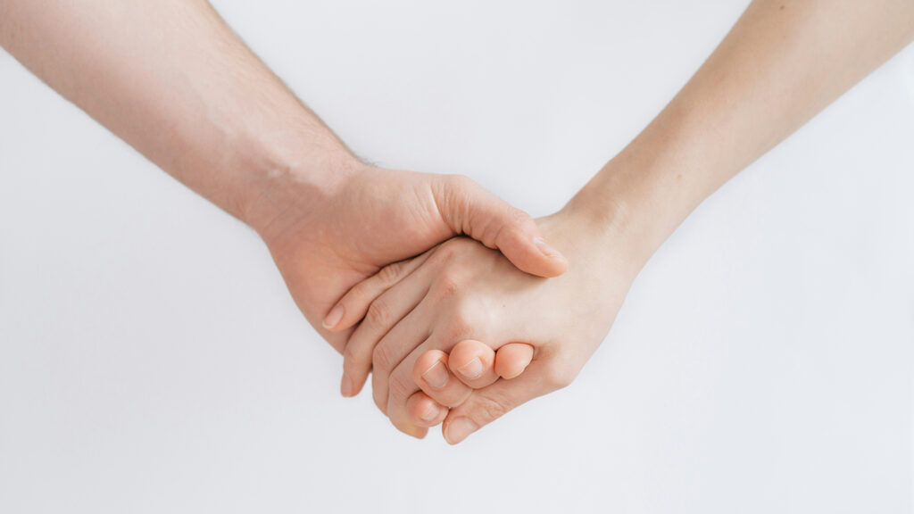 A pair of hands holding on an off-white background.